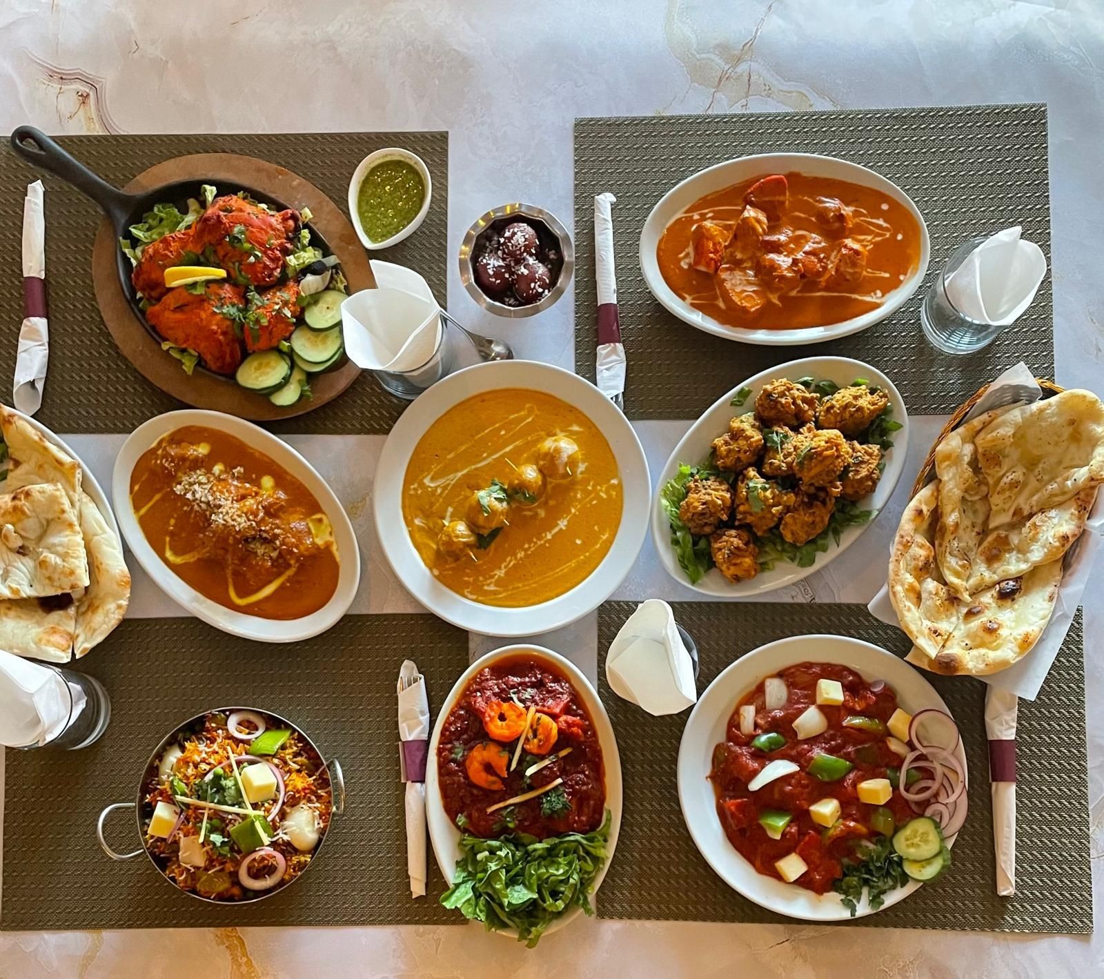 Assorted Indian dishes including curries, naan, and appetizers served on a dining table.